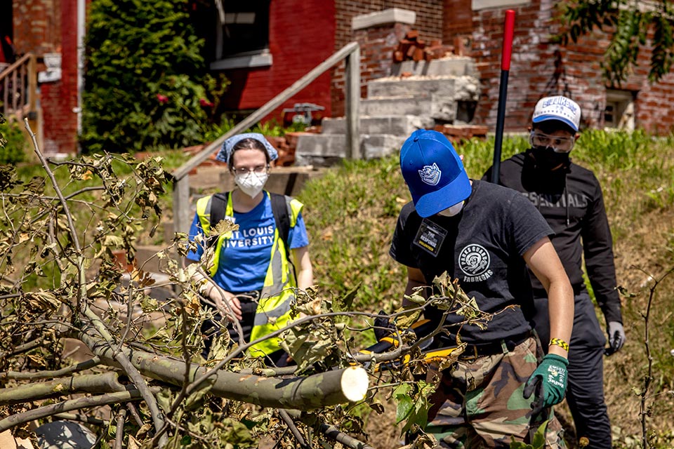 Three people clean up tree debris.