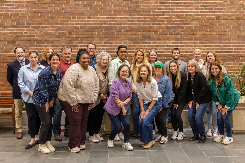 Archdiocese Cohort 2025 group of people smiling and posing in front a brick wall