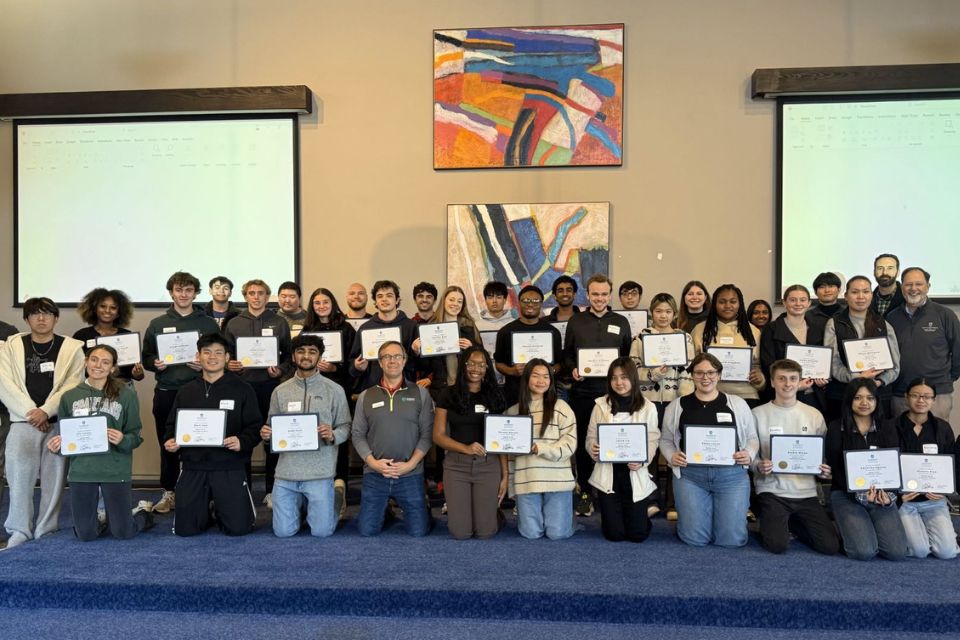 Leadership Academy 2025 large group of people posing and holding certificate in front of projector screens