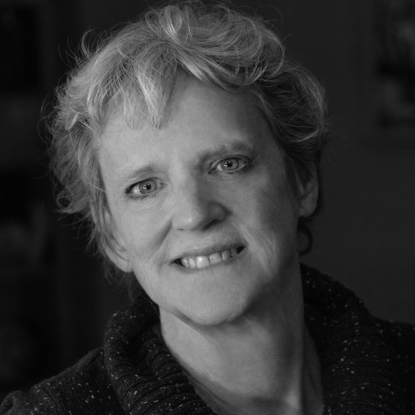 Black and white headshot of Eleanor Heartney, gazing at the camera smiling with her head tilted slightly to the left