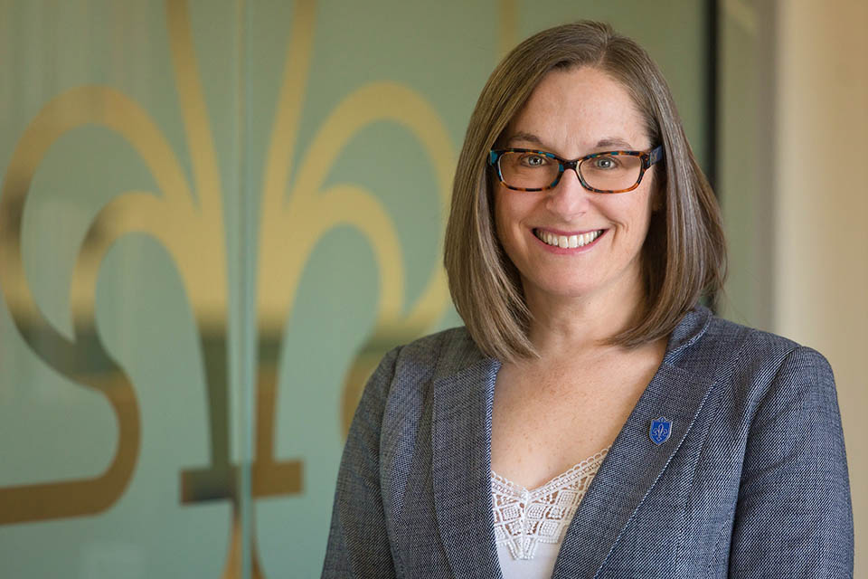a woman wearing glasses and a grey blazer