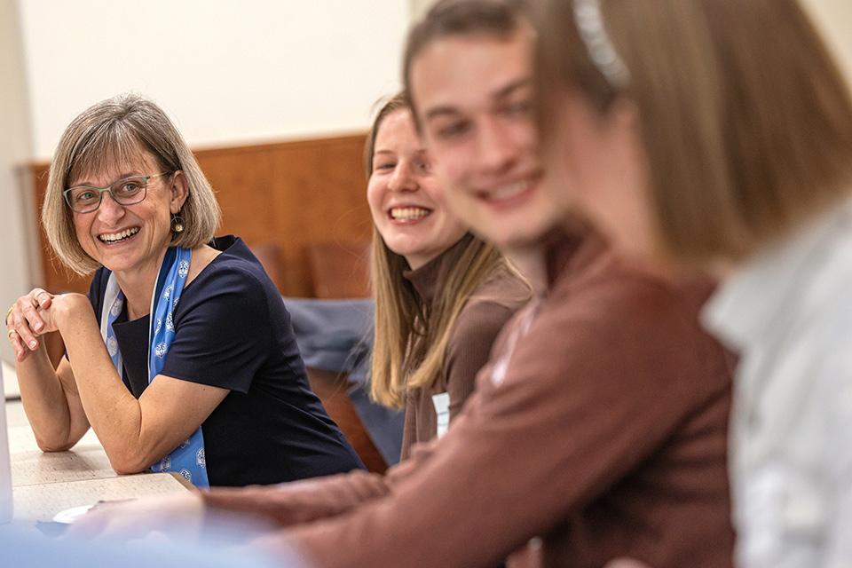 Kathy Feser laughs and chats with students at a table
